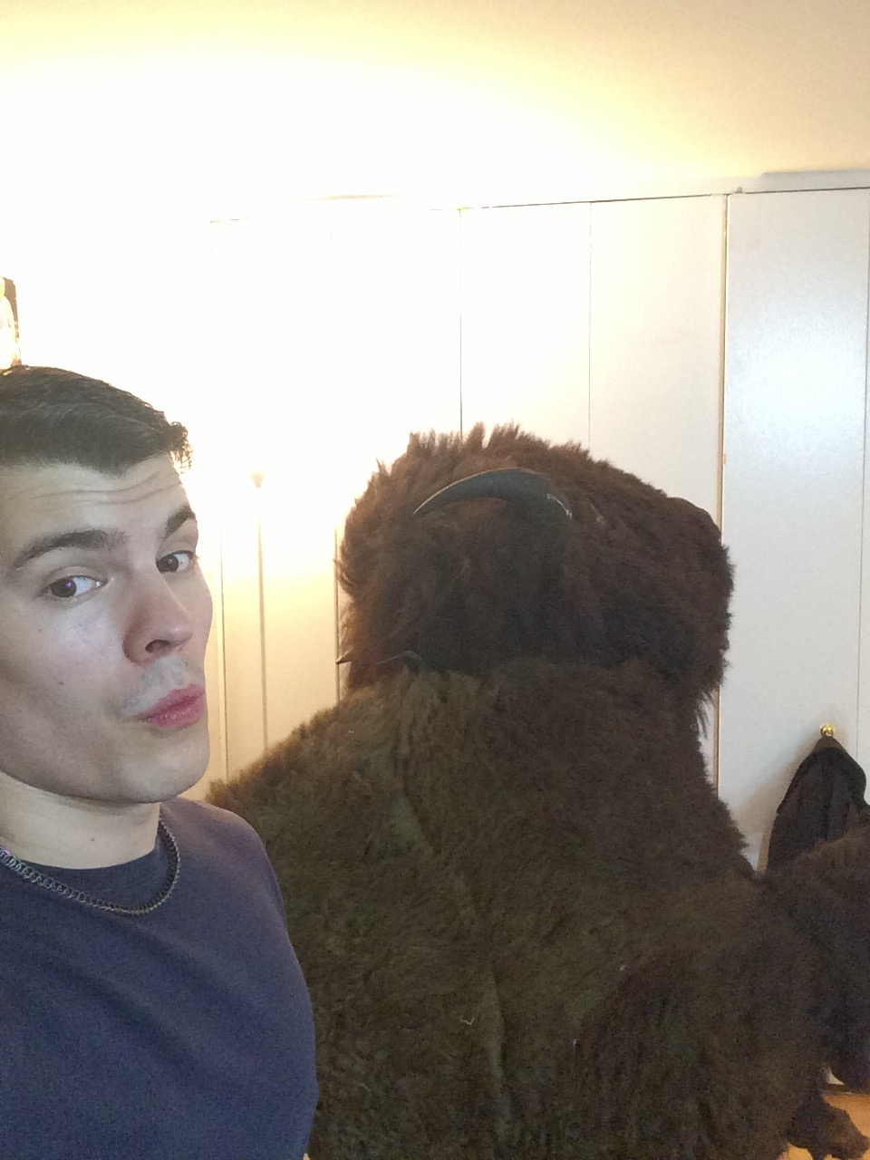 A crew member taking a selfie with the buffalo costume in the apartment
