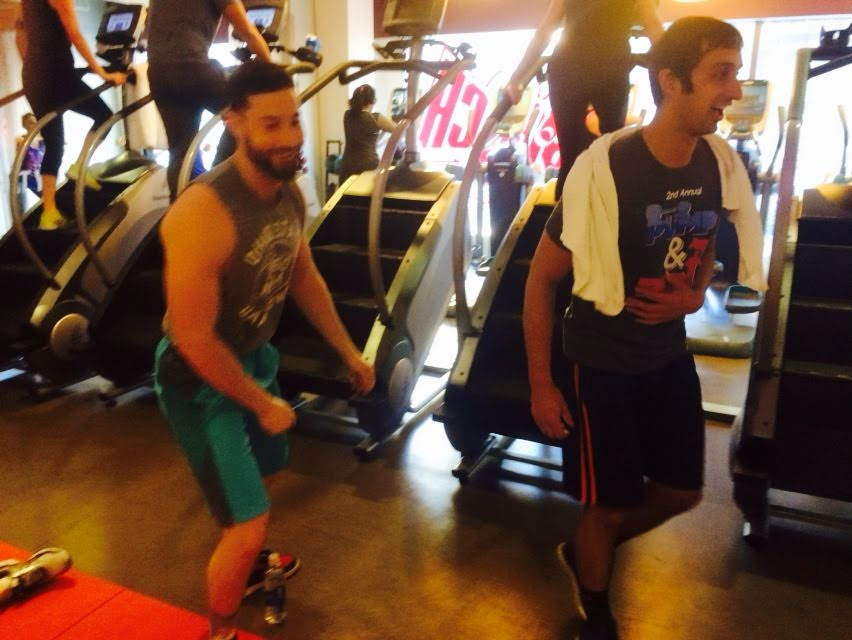 Two men working out on stair machines at a gym