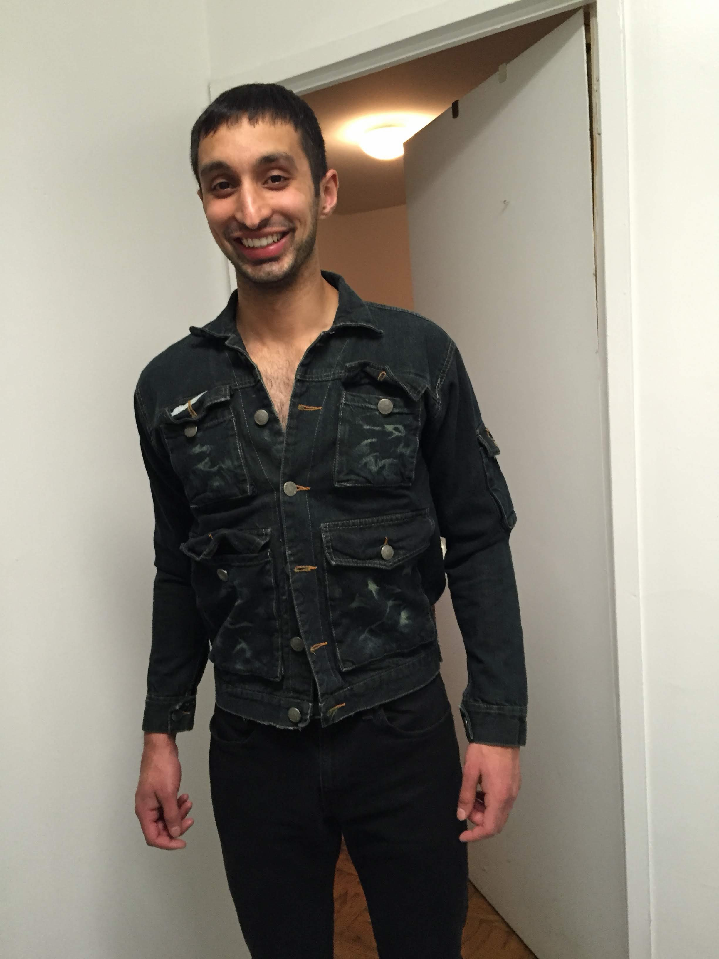 Vivek smiling in a distressed denim jacket in an apartment hallway