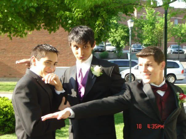 Three young men in suits striking a pose outside before a high-school dance, Vivek in the center with a purple tie