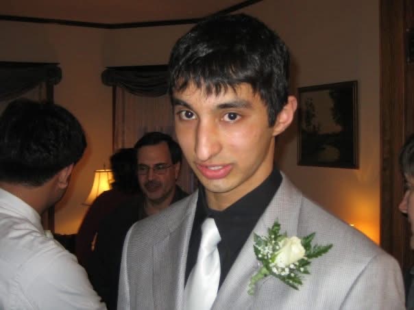 Vivek in a grey suit and white rose boutonnière, dressed for a high-school dance