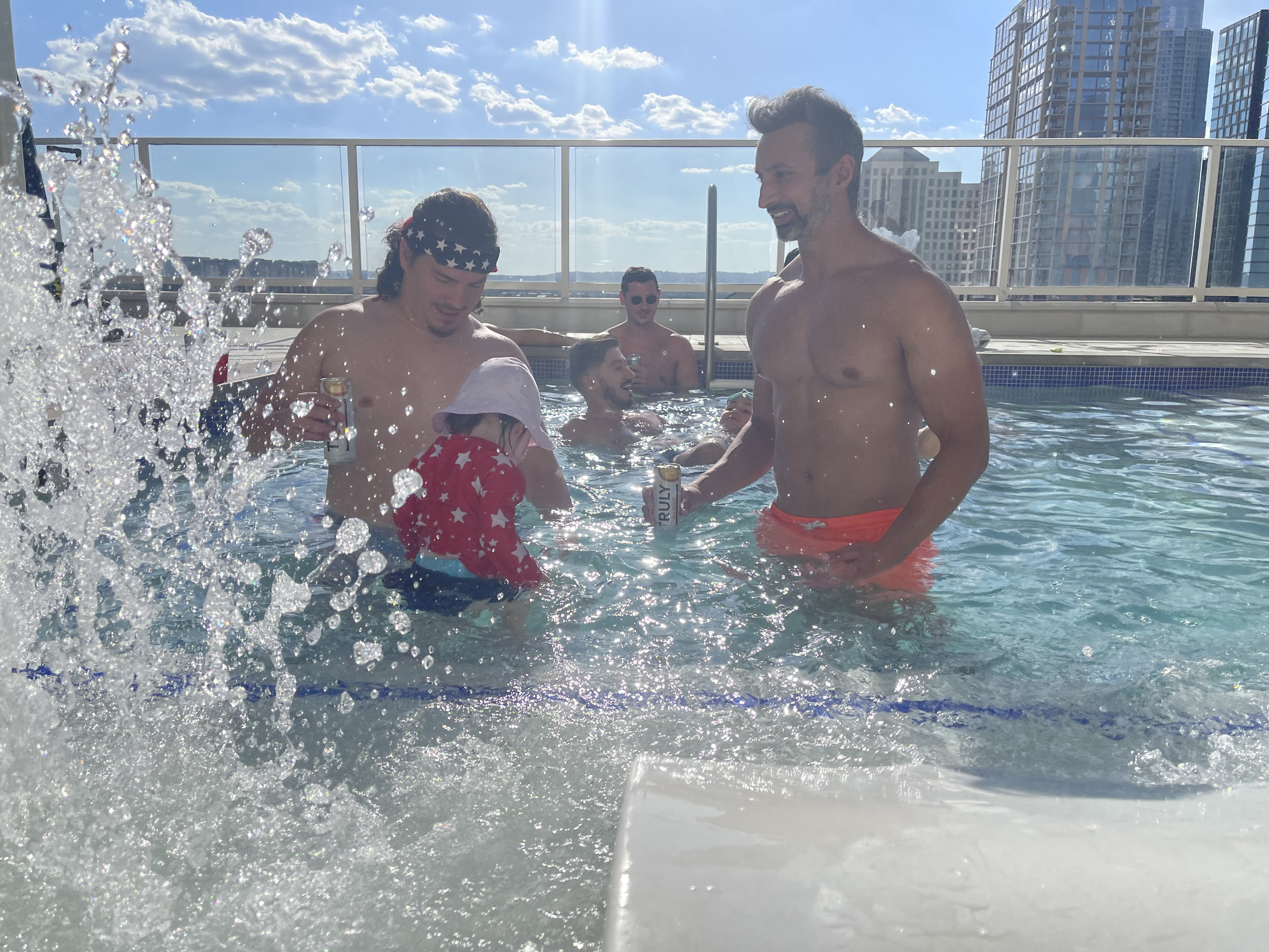 Vivek, Justin, and Justin’s daughter at a rooftop pool, city skyline behind them