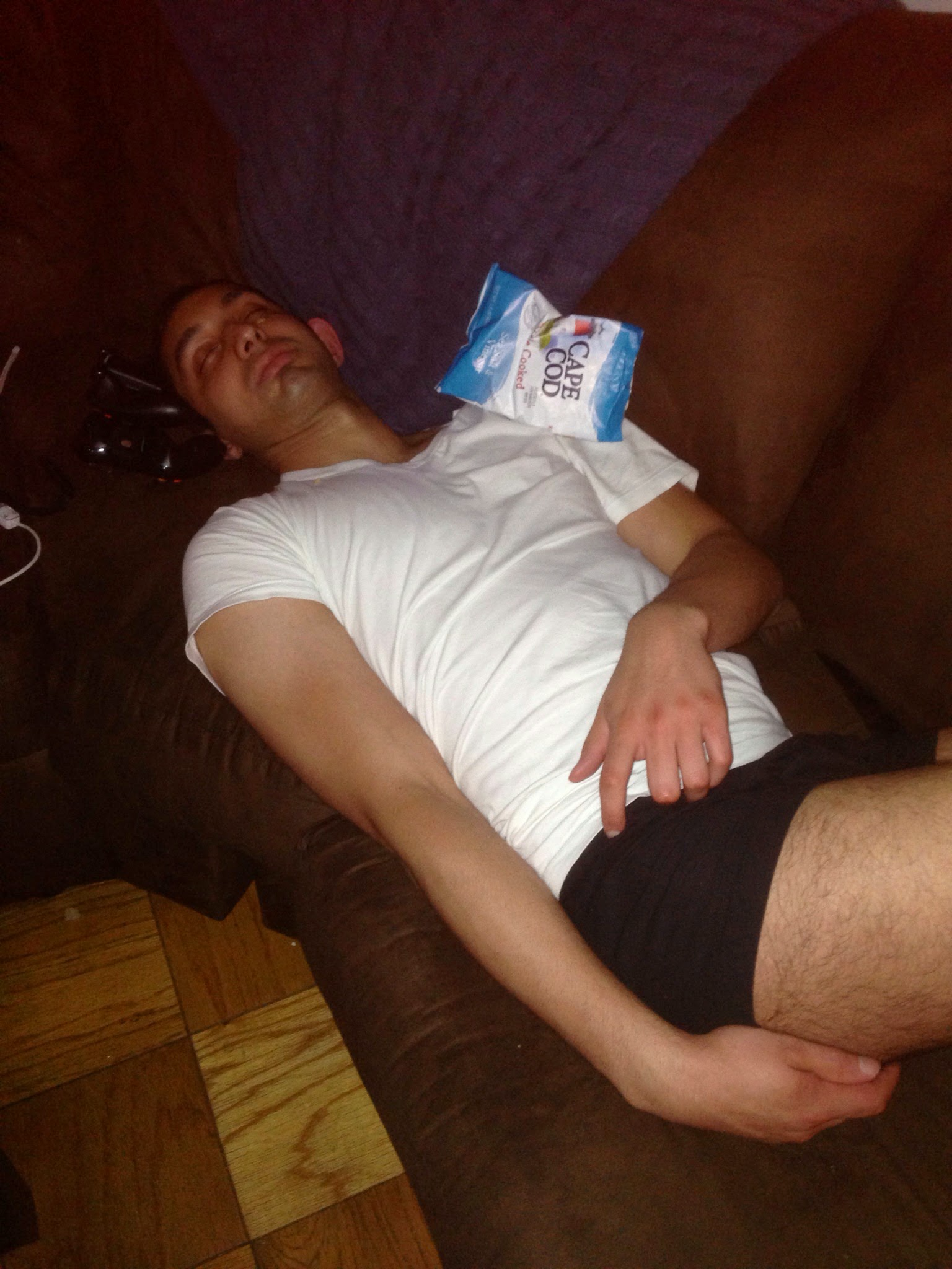 Vivek asleep on a couch at a party with a bag of Cape Cod chips resting on his chest